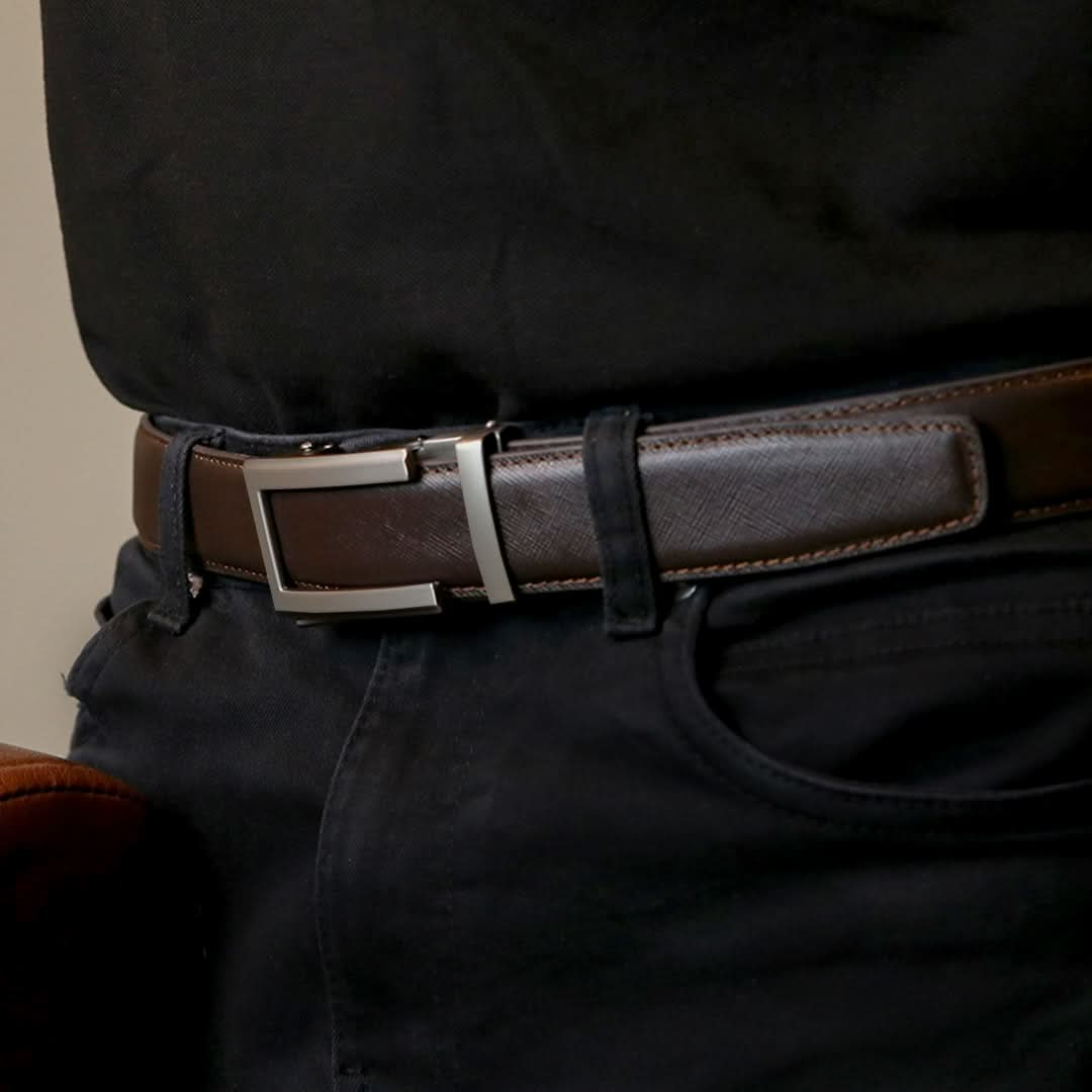 A man wearing an adjustable belt with a smooth brown leather strap featuring textured line patterns and a sleek silver buckle.