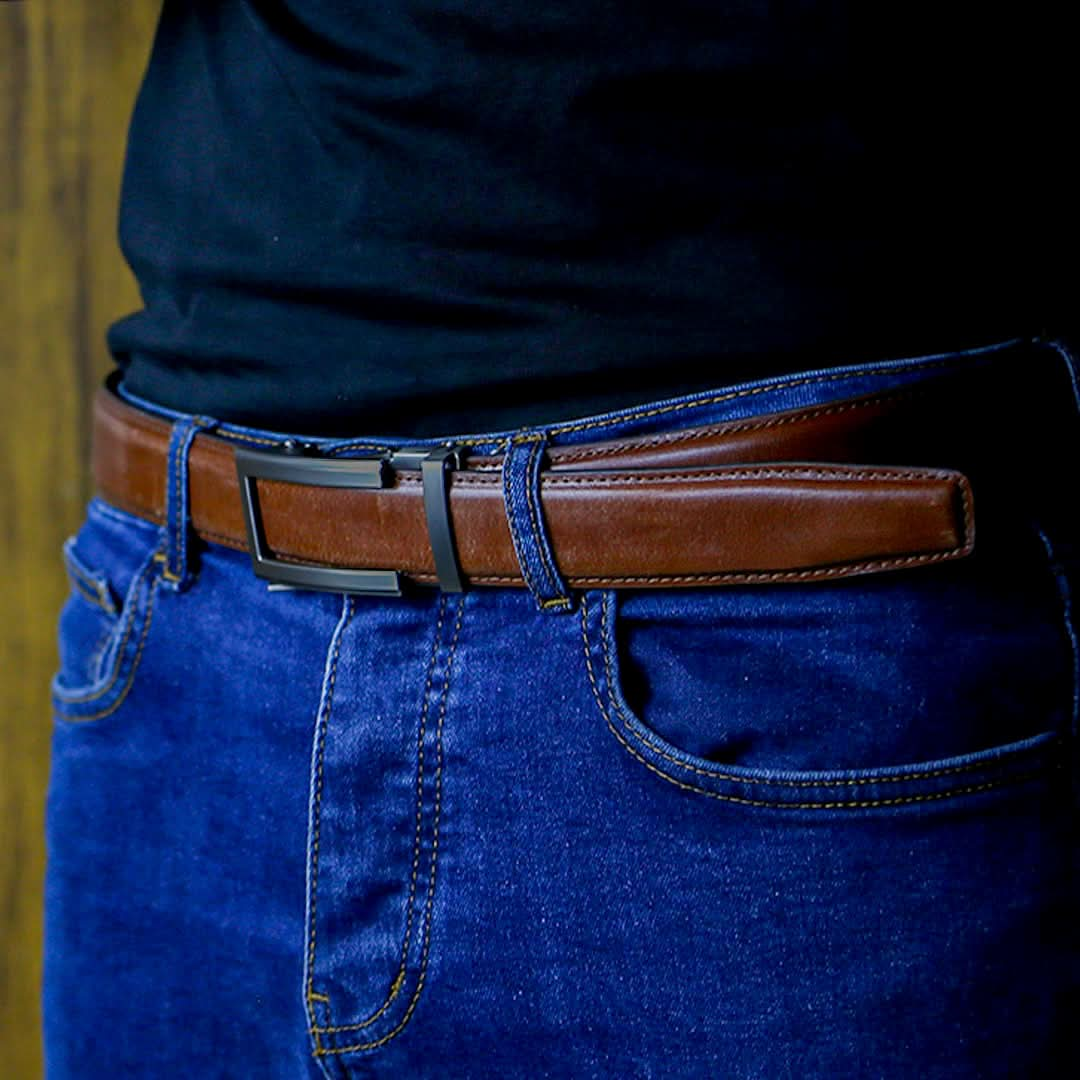 Close-up of a stylish brown leather adjustable men's belt with a sleek gunmetal buckle, worn with jeans.